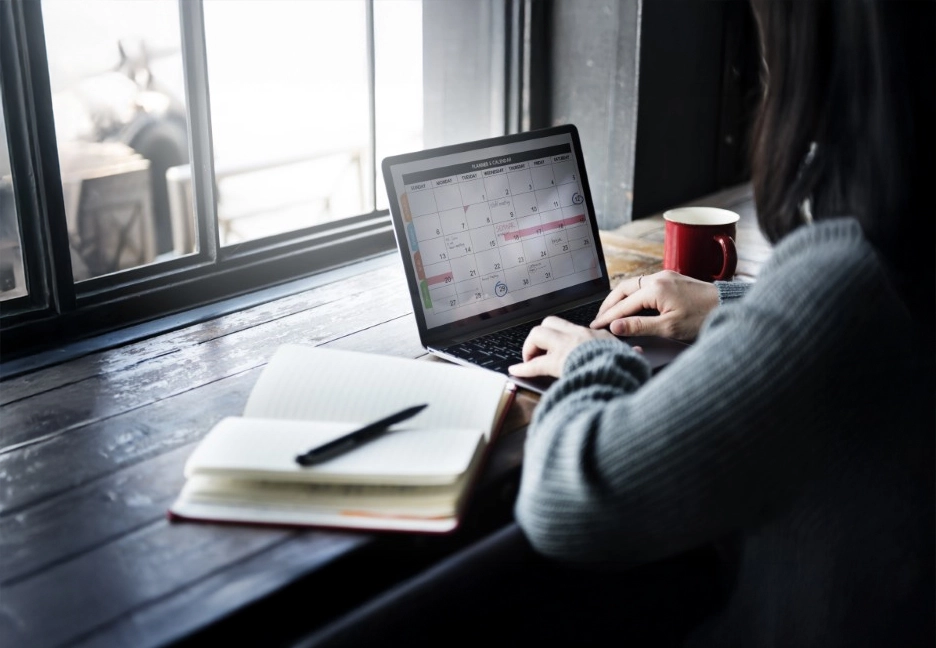 person on laptop with a book