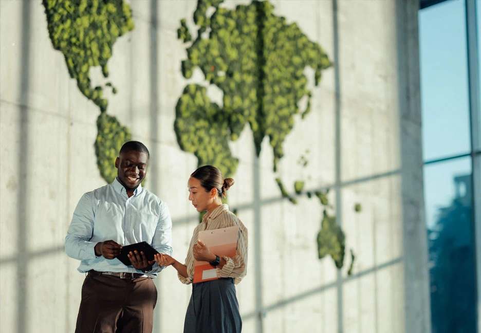 man and woman talking next to a world map