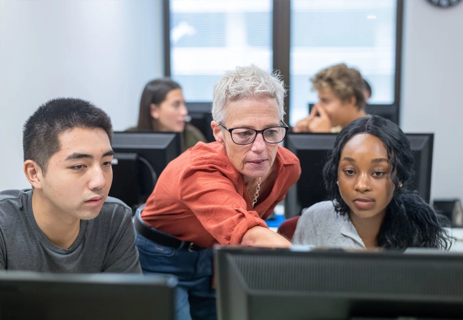 female teacher helping students on computer