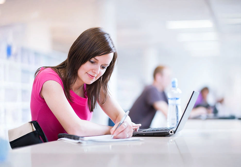 girl doing class work on notebook and laptop