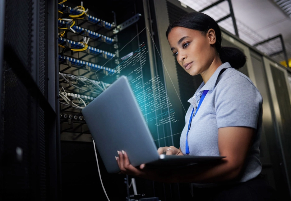 female IT employee on laptop in server room