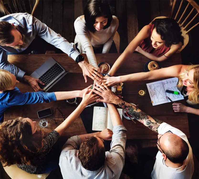group of employees with hands together over a table