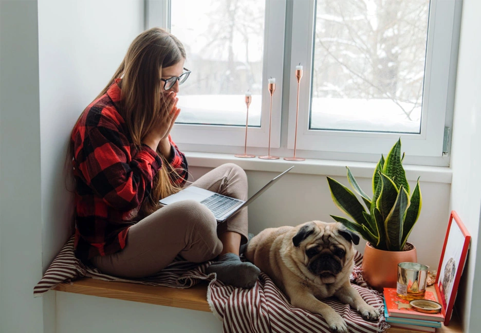 student on laptop by a window with snow outside